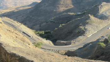 Rock face with road cutting into the hills. Cars driving on the road